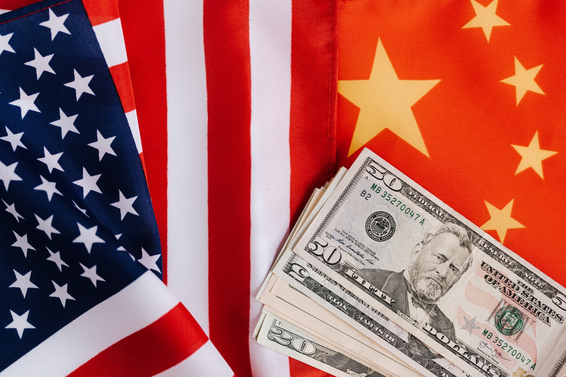 The U.S. and China have a complex and changing relationship. Pictured is an American flag, a Chinese flag, and American dollars.